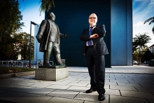 Armin Asper, Schulleiter des Martin-Andersen-Nexö-Gymnasium in Dresden, posiert vor seiner Schule neben der Statue von Martin Andersen Nexö.